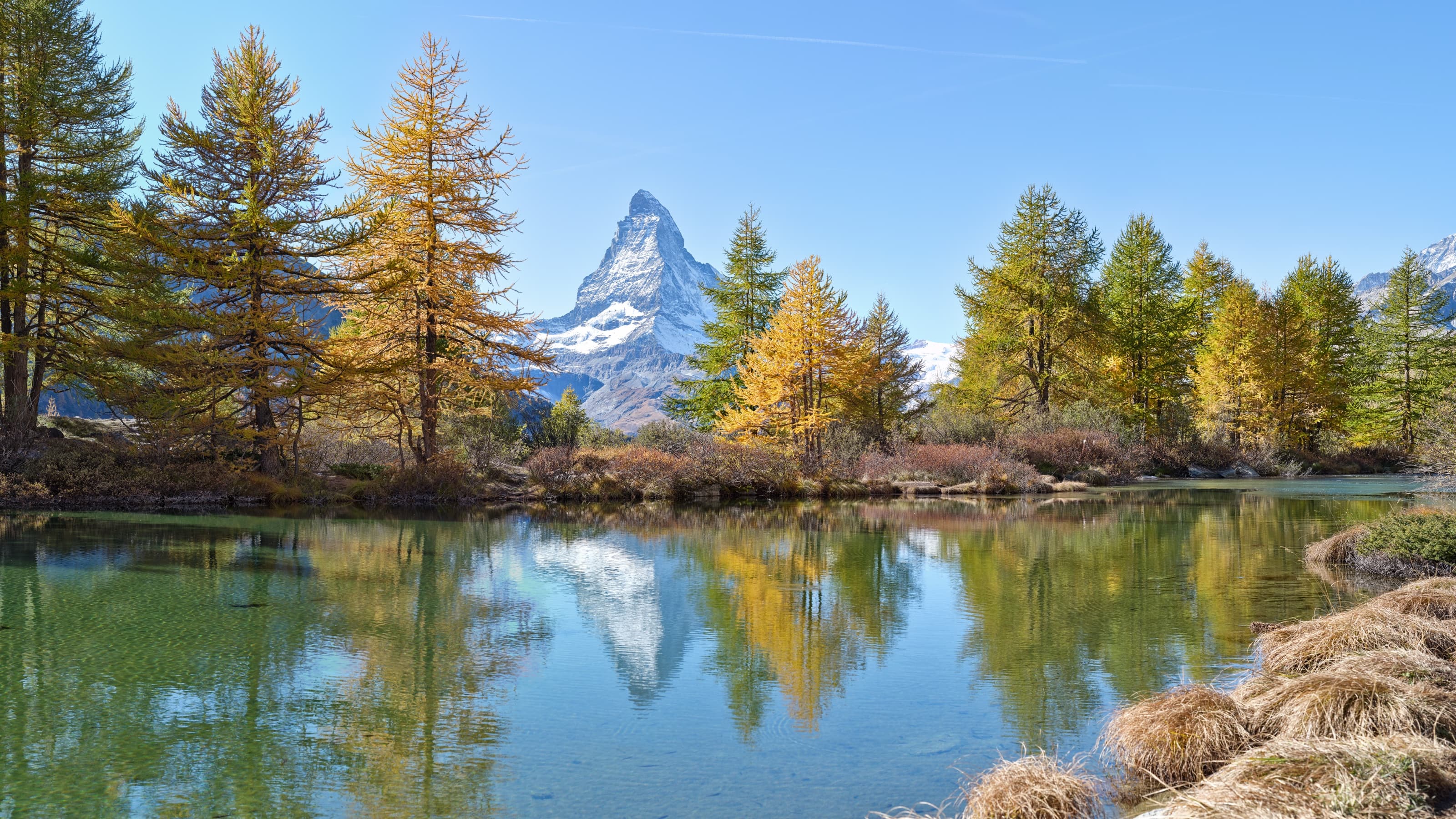 The iconic Matterhorn reflected in a still alpine lake in Zermatt during golden hour