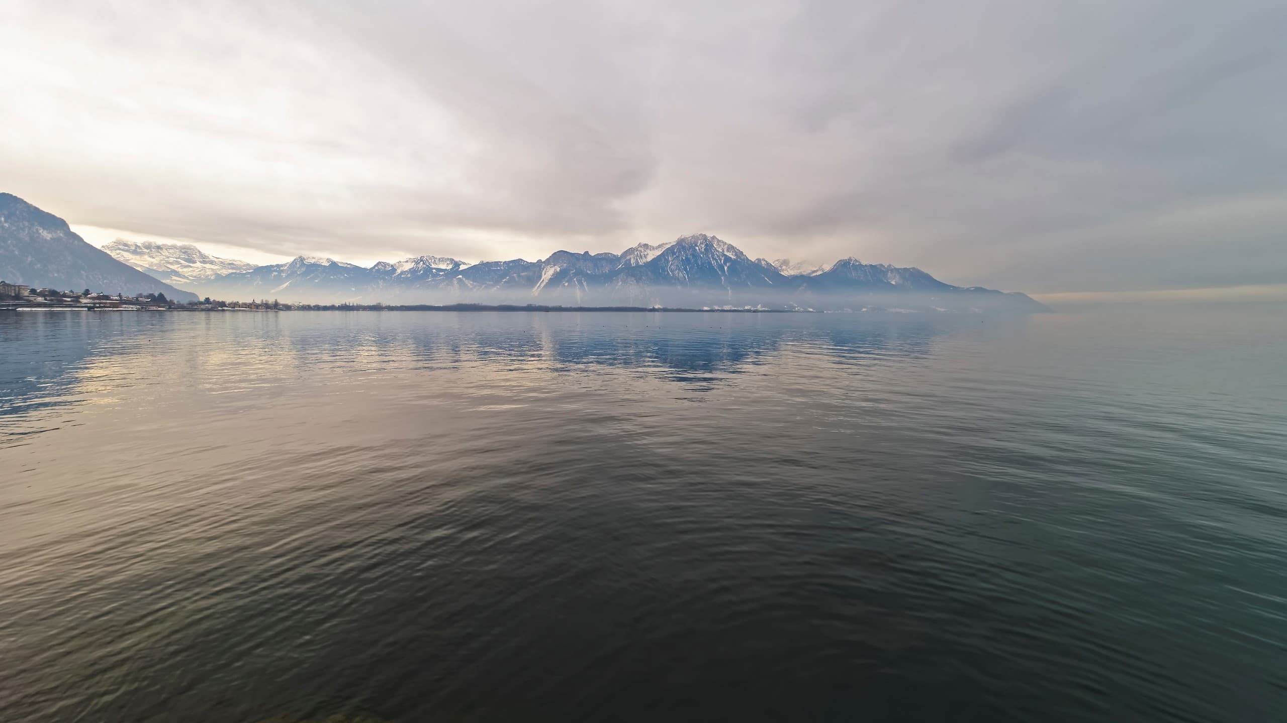 Calm Lake Geneva waters and distant Alpine mountains viewed from Montreux